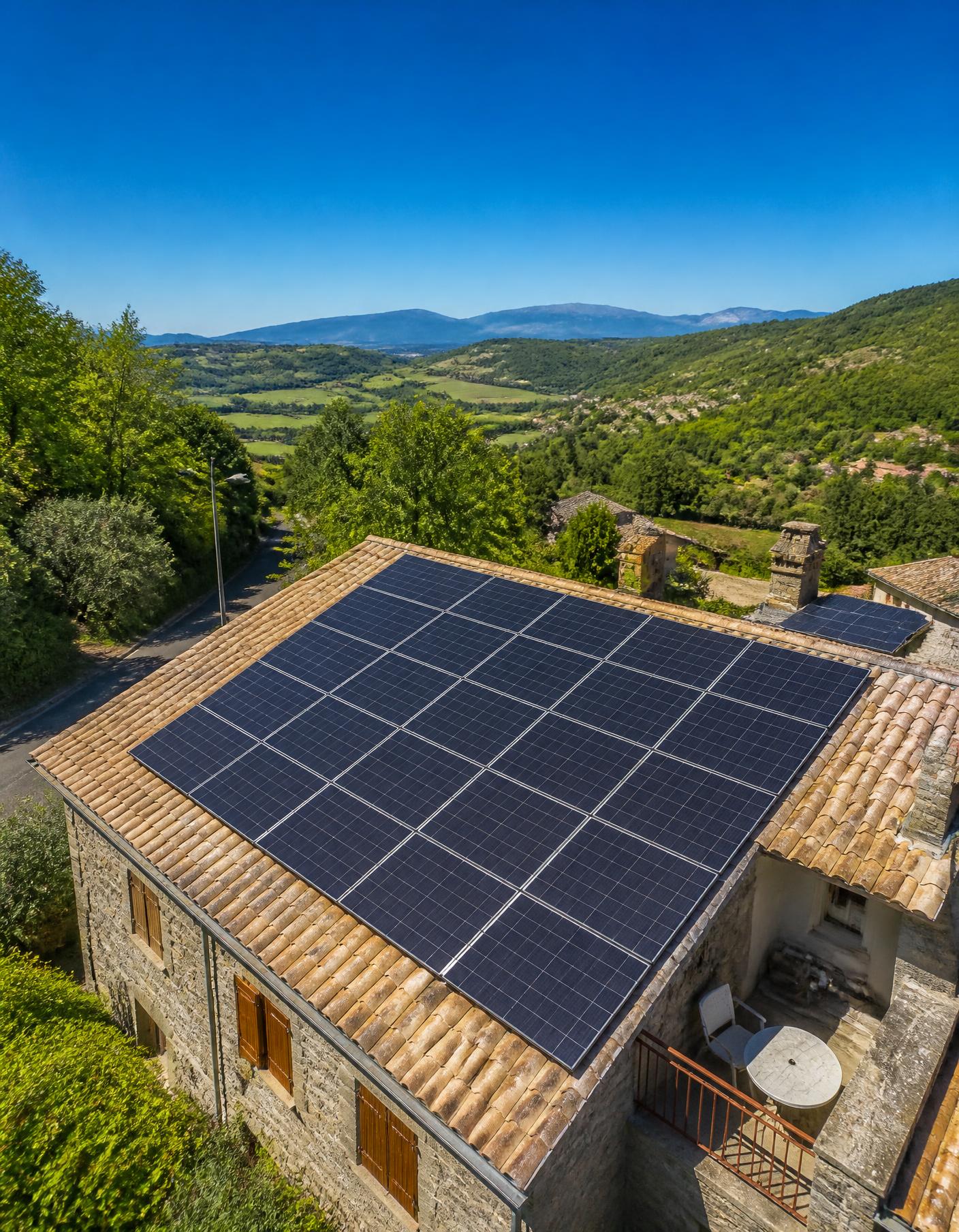 Panneaux solaires sur le toit d'une maison ardéchoise face à la vallée